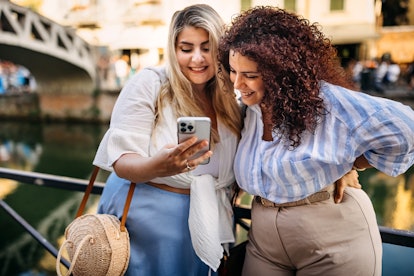 Two friends look at self love captions for Instagram to decide which ones to post. 
