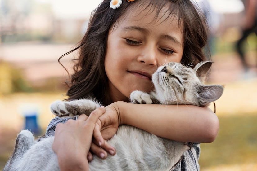 child snuggles her cat in an article about when international cat day is in 2022