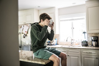 Teenage boy eating breakfast cereal in kitchen
