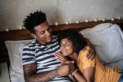Happy couple lying on the bed at home. Here’s your July 29 zodiac sign daily horoscope.
