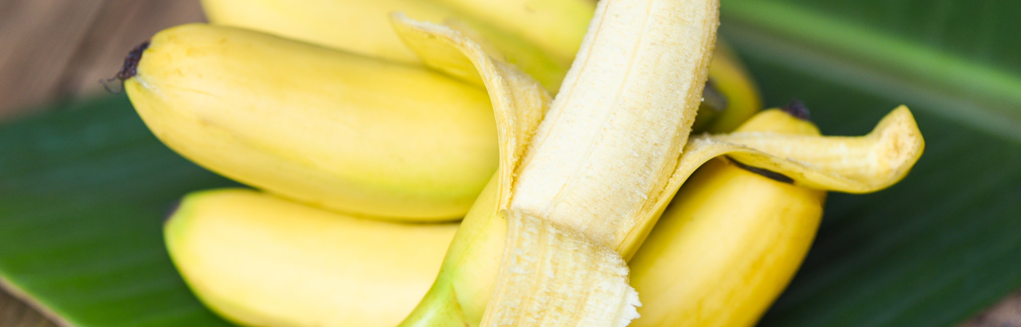 Banana peel ready to eat and ripe banana fruit on banana leaf background