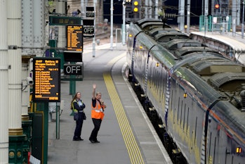 Train staff wave off a train at Waverley Station in Edinburgh, as train services continue to be disr...