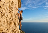 A woman rock climbs up a cliff. These are the most intense zodiac signs.