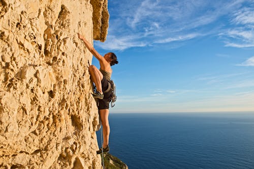 A woman rock climbs up a cliff. These are the most intense zodiac signs.
