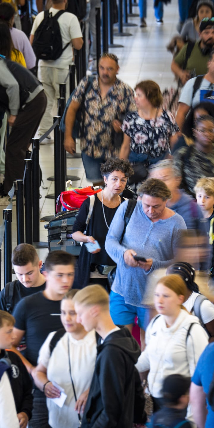Passengers queue to check-in for flights at the Schiphol Airport on 29 July 2022. - Schiphol has bee...