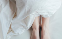 Close-up of a woman's feet covered with a duvet