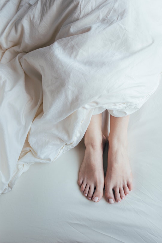 Close-up of a woman's feet covered with a duvet