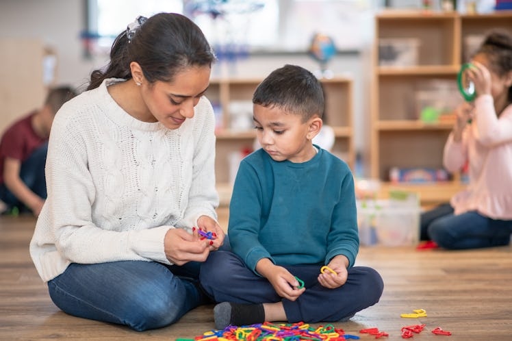 A boy is guided by his teacher while playing in daycare.