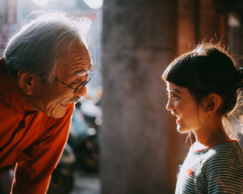 Profile view of cute young mixed race girl smiling at her grandfather, list of boundaries for grandp...