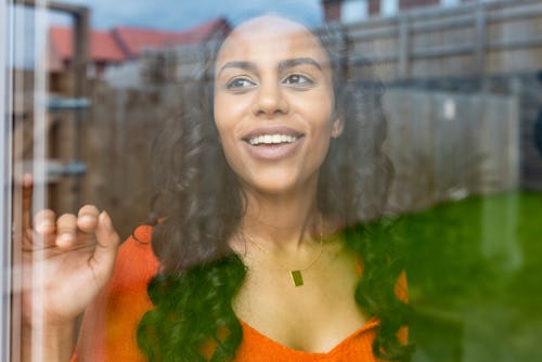 A woman looks out a window. How the July 2022 full Buck moon will affect your zodiac sign.