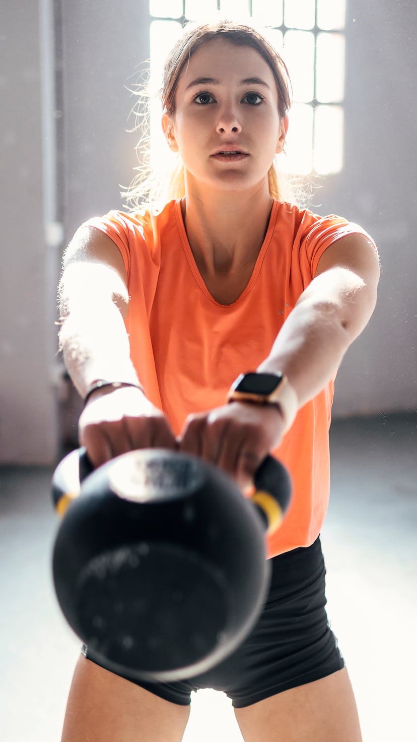 A woman in an orange shirt doing a kettlebell workout for her glutes