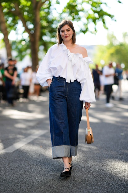 PARIS, FRANCE - JULY 03: A guest wears a white ruffled shoulder-off / puffy long sleeves shirt, navy...