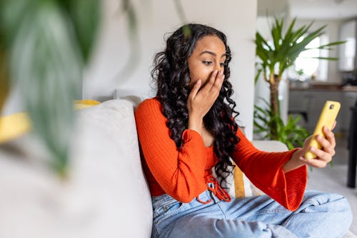 Woman suppresses a gasp while looking at her phone. How to delete or pause your bumble account.