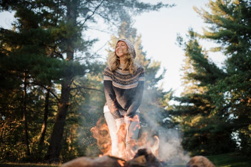 A woman leans in front of a campfire. Your guide to fire signs: everything you need to know about fi...