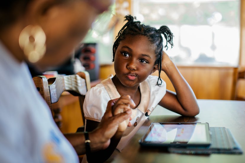 Young child getting help with her homework. digital tablet is lying on the table in front of the you...