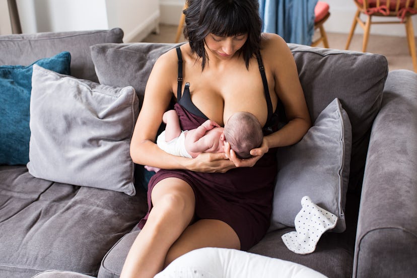 Mother breastfeeding newborn baby son on sofa in an article about newborn choking while breastfeedin...