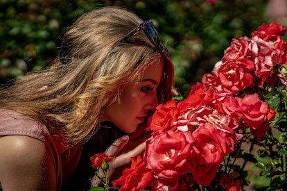 Young woman smelling flowers after reading her September 2022 horoscope.