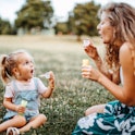 Mother and daughter playing with bubble soap in nature