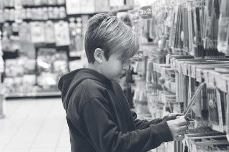 Boy shopping for school supplies in a supermarket.