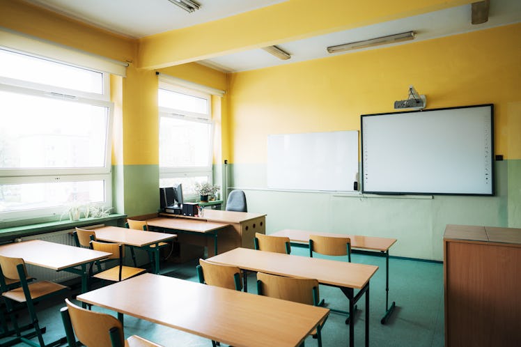 Rear view of an empty classroom in elementary school. Wooden chairs and desks inside the classroom w...