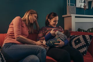 Woman watches another woman breastfeed her baby. 