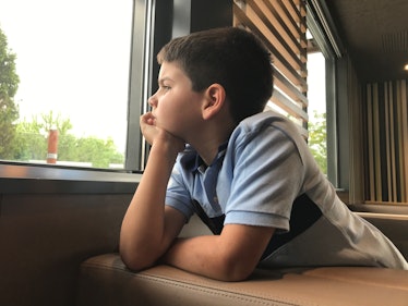 A bored child looking out of a window.