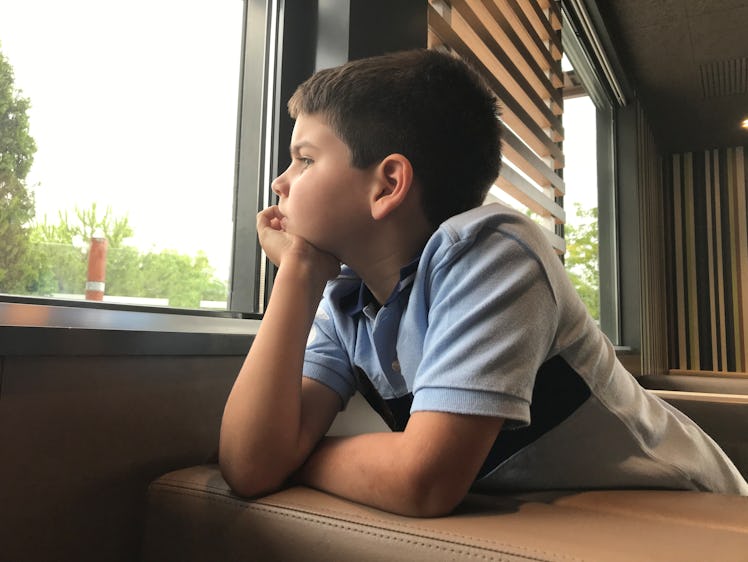 A bored child looking out of a window.