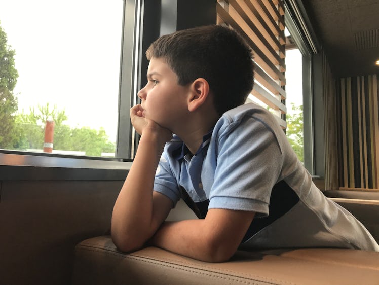 A bored child looking out of a window.