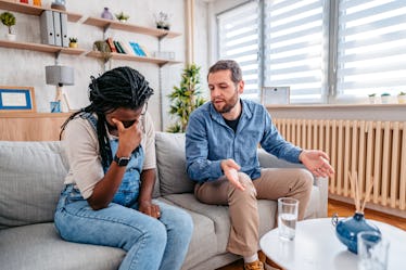 年轻怀孕混血夫妇认为在客厅里的沙发上。