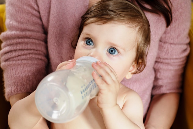 baby staring at the camera drinking a bottle of formula in an article about reasons why some women c...