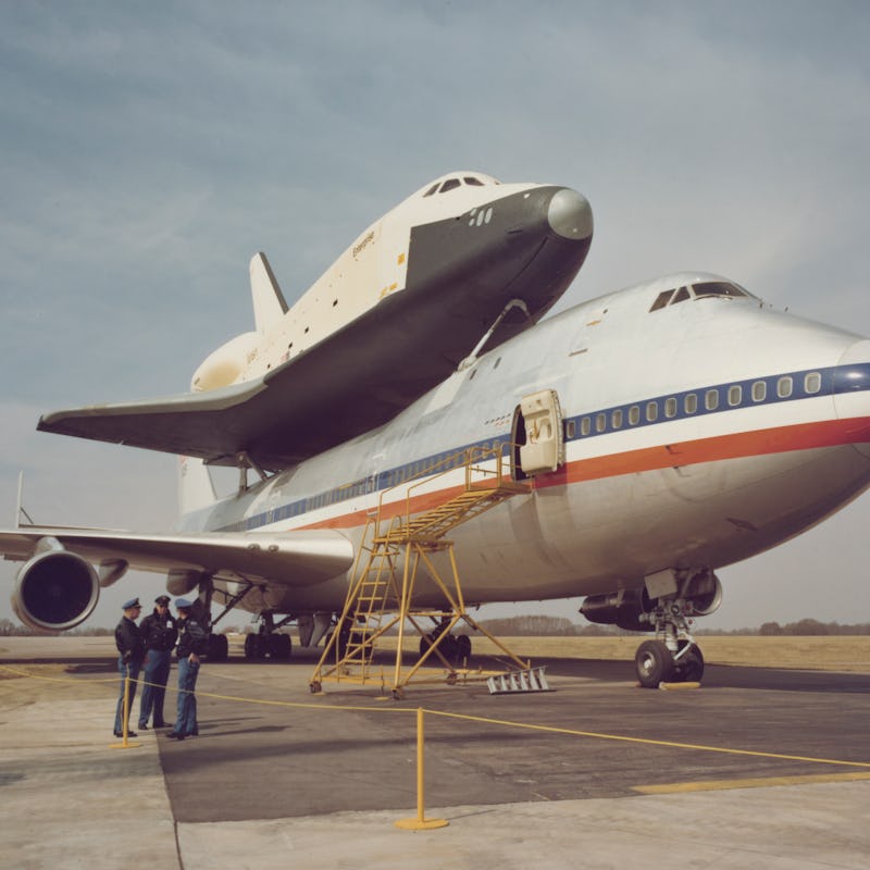 Space Shuttle Enterprise (OV-101) arrives atop NASA 905, a 747 carrier aircraft in the background, a...