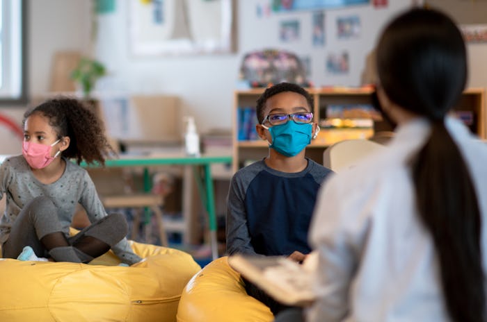 A small group of three students sit spread evenly apart on beanbag chairs as they participate in cla...