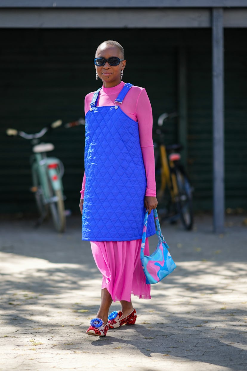 COPENHAGEN, DENMARK - AUGUST 10: A guest wears navy blue sunglasses, a pink long sleeves pleated dre...