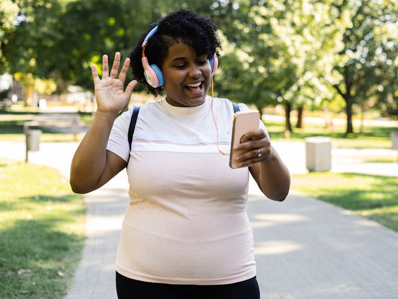 Young woman walking in the park and enjoying music when Pluto retrograde 2022 ends on Oct. 8.