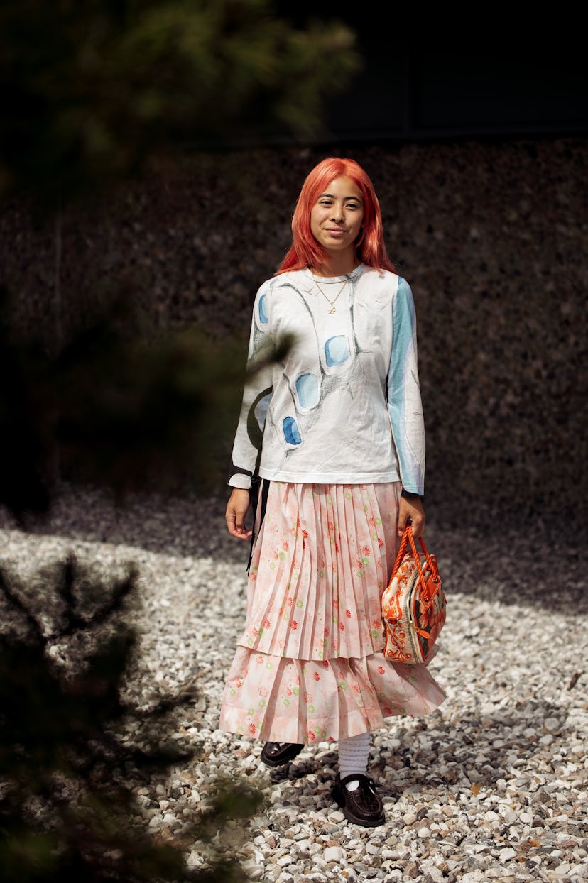 COPENHAGEN, DENMARK - AUGUST 09: A guest wearing pink / orange long skirt, white / blue top with a p...