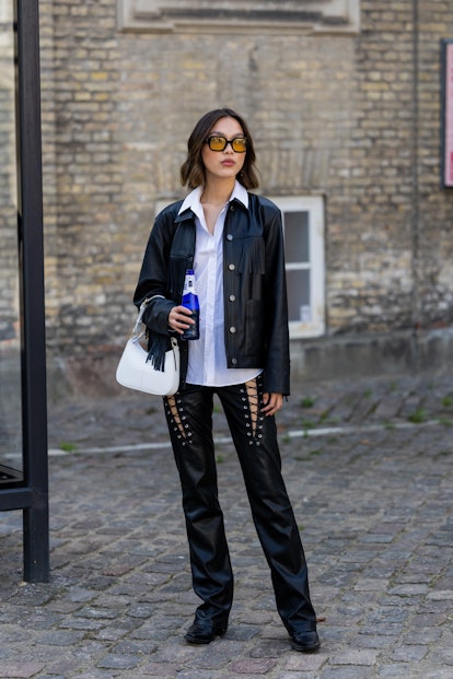 COPENHAGEN, DENMARK - AUGUST 09: A guest is seen wearing black laced leather pants, jacket with frin...