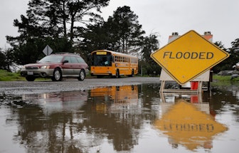 A car passes by a flooded part of Spinnaker Road during a break in the rain near Cesar Chavez Park i...