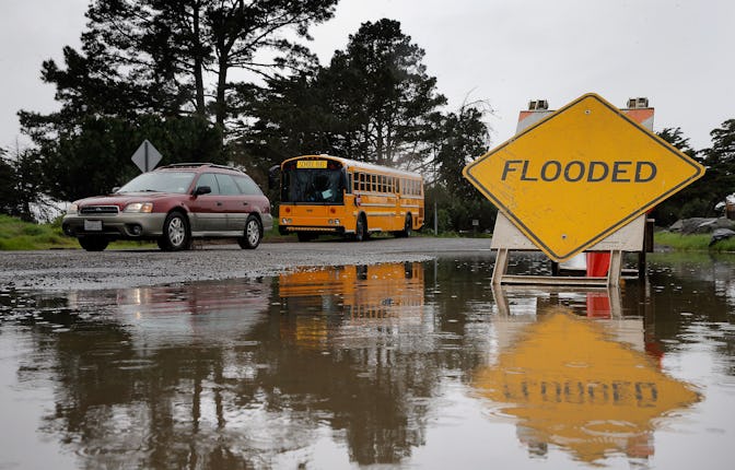 A car passes by a flooded part of Spinnaker Road during a break in the rain near Cesar Chavez Park i...