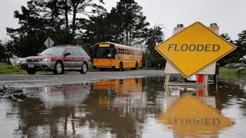 A car passes by a flooded part of Spinnaker Road during a break in the rain near Cesar Chavez Park i...