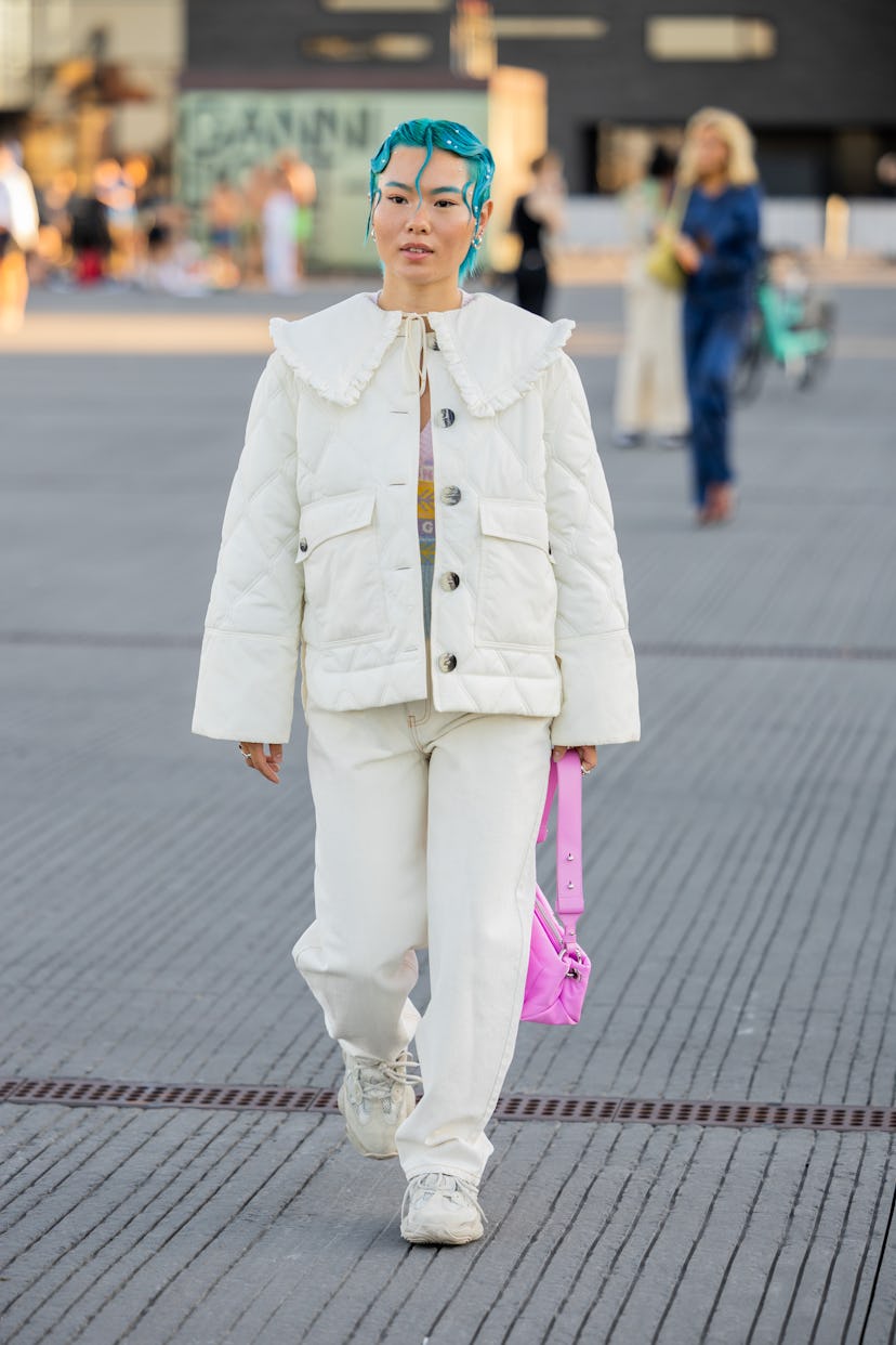 COPENHAGEN, DENMARK - AUGUST 11: A guest is seen wearing white jacket, pants, pink bag outside Ganni...