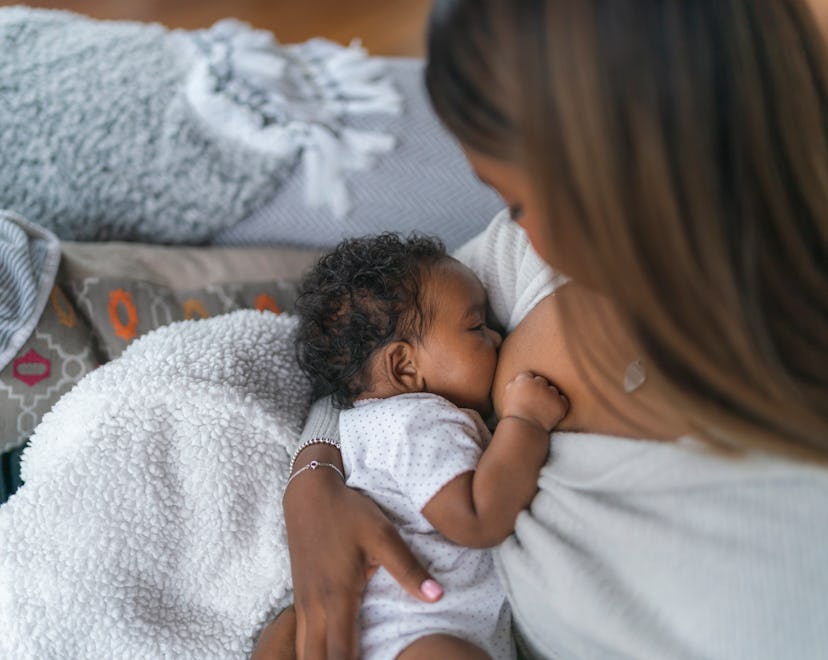 A woman breastfeeding her baby daughter in an article about cramping while breastfeeding