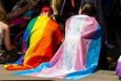 抗议者披着彩虹骄傲和跨性别者旗帜等待参加伦敦跨性别者+骄傲…