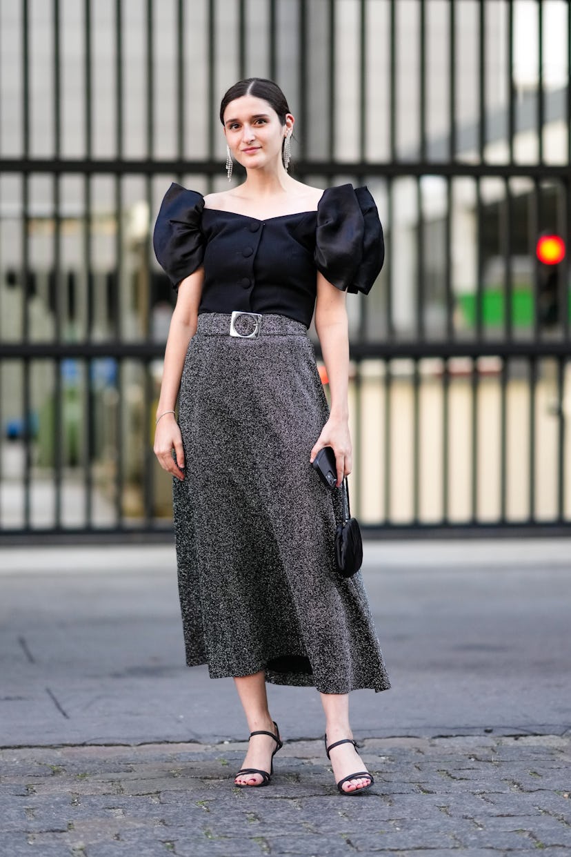 COPENHAGEN, DENMARK - AUGUST 10: A guest wears silver rhinestones fringed pendant earrings, a black ...