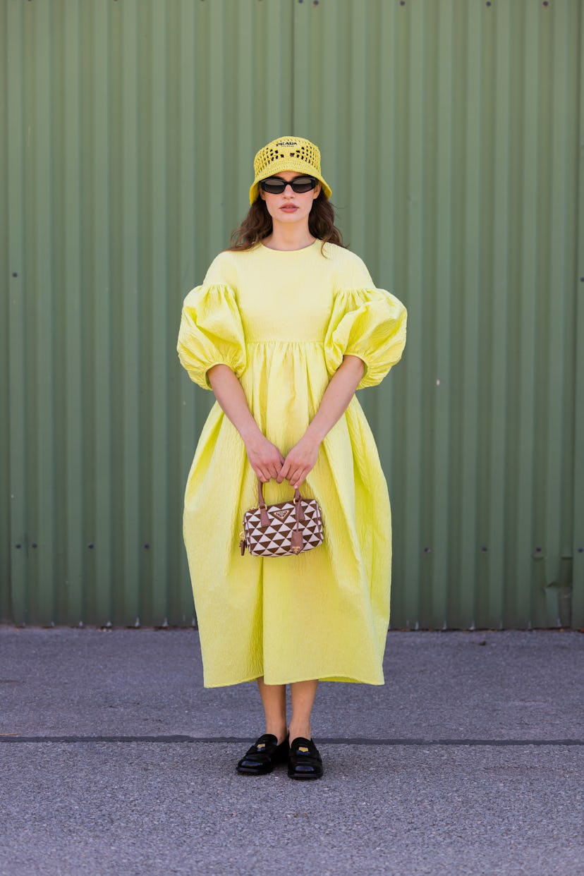 COPENHAGEN, DENMARK - AUGUST 10: Lea Naumann seen wearing yellow dress, Prada hat, bag, loafers outs...