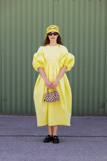 COPENHAGEN, DENMARK - AUGUST 10: Lea Naumann seen wearing yellow dress, Prada hat, bag, loafers outs...
