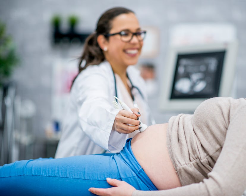 A pregnant Caucasian woman is indoors in a medical clinic. She is lying down while having an ultraso...
