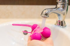 Woman cleaning her waterproof sex toy after using it in the shower 