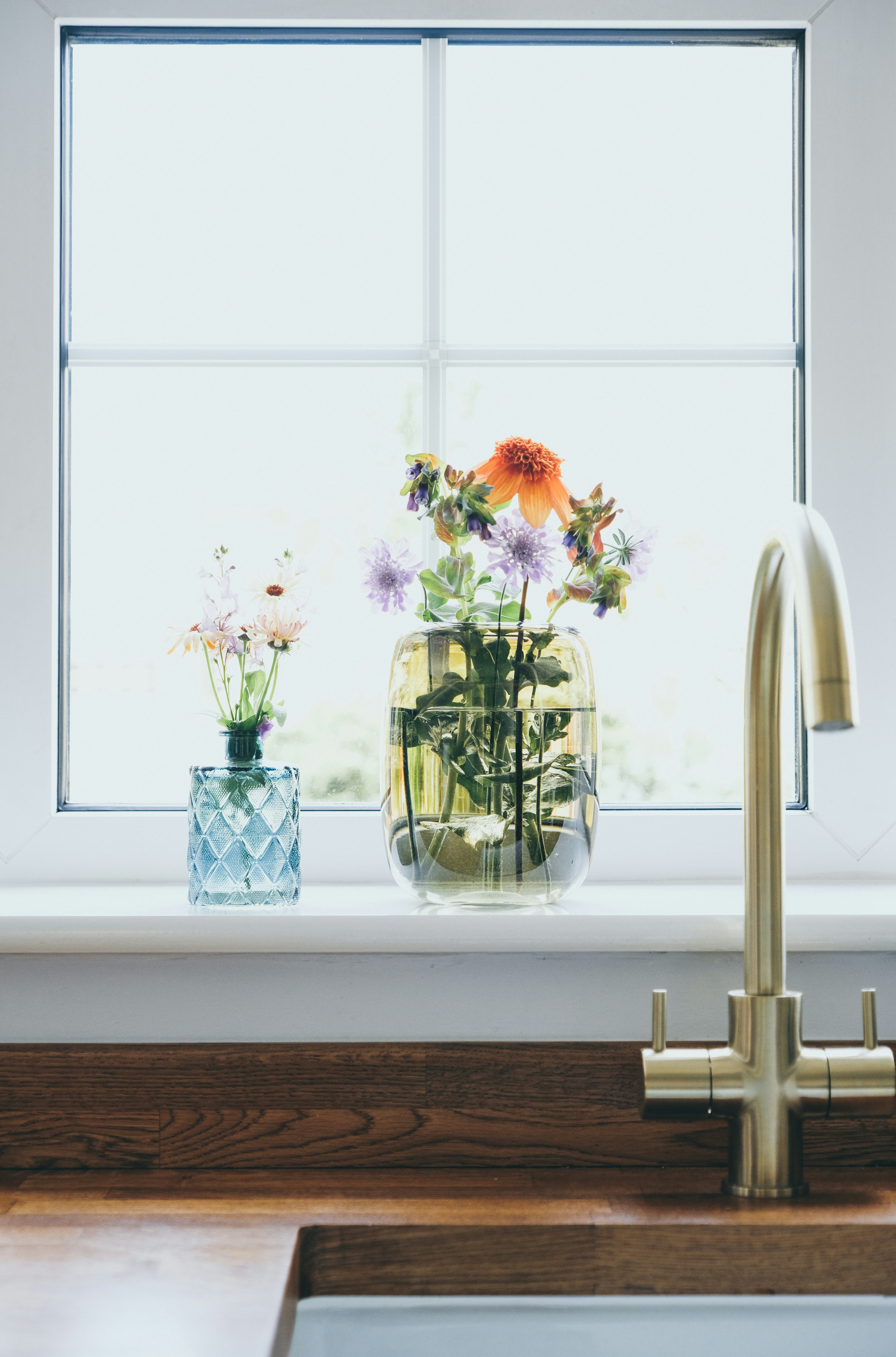 Fresh cut flowers in vase on kitchen window sill