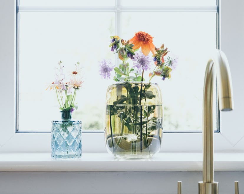 Fresh cut flowers in vase on kitchen window sill