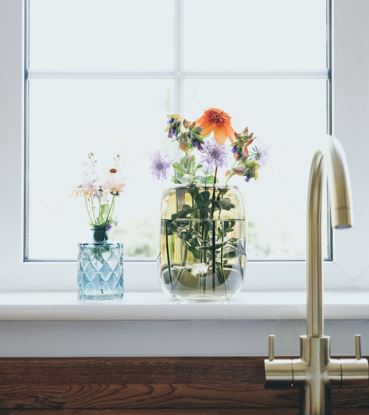 Fresh cut flowers in vase on kitchen window sill